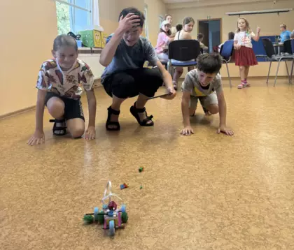 Chłopcy sterują samochodzikiem złożonym z klocków lego.