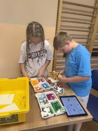 Chłopak i dziewczyna składają klocki lego.