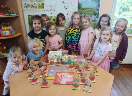 Na zdjęciu widać grupę dziewczyn stojących przed swoimi pracami dla mamy.
