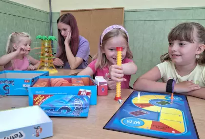 Dziewczynki siedzą przy stole i grają w gry planszowe.