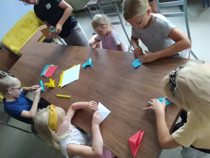 Dzieci składają metodą origami latające stateczki.