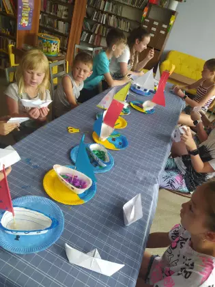 Dzieci przyklejają statki do talerzyka papierowego.
