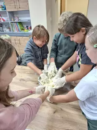 Dzieci wyrabiają ciasto na pizzę.