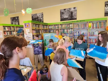 Dzieci przyklejają butelkę z listem na obrazek.