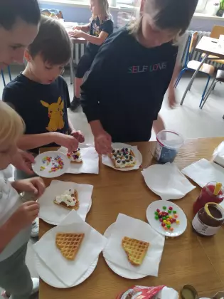 Dzieci degustują gofry z bitą śmietaną.