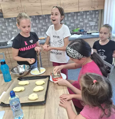 Dziewczyny formują jagodzianki i układają je na blaszce do pieczenia.