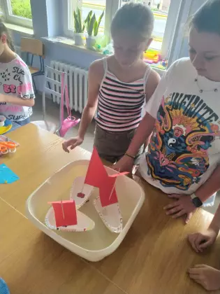 Dzieci puszczają stateczki na wodę.