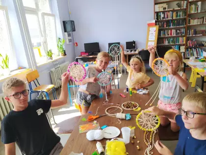 Dzieci pokazują kolorowe łapacze snów, które wykonali.