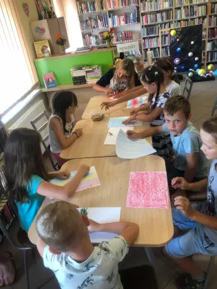 Dzieci kolorują kredkami szalik dla Szymborskiej.