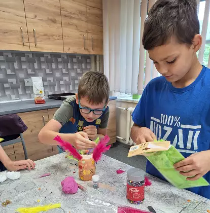 Chłopcy ozdabiają wyklejone masą solną słoiki.