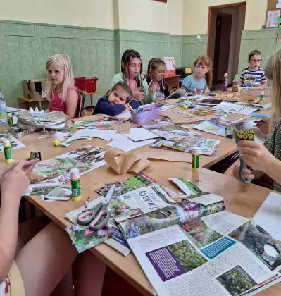 Dzieci wykonują kolaże z gazet.
