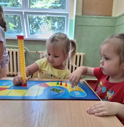 Dziewczynki siedzą przy stole i grają w gry planszowe.