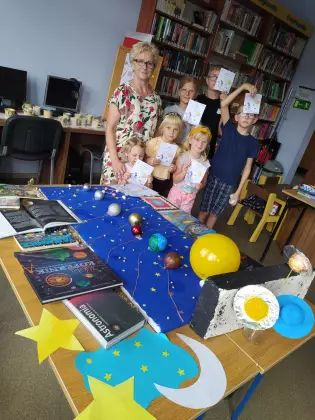 Uczestnicy zajęć stoją przed makietą kosmosu, którą wykonali.