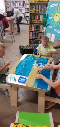 Dzieci malują farbkami morze.