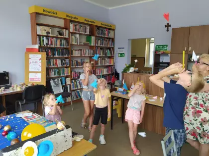 Dzieci dmuchają rurką stateczki kosmiczne.