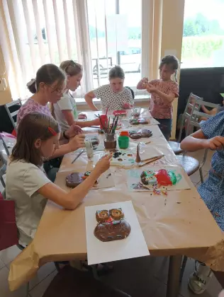 Dzieci malują farbami gipsowe sówki.