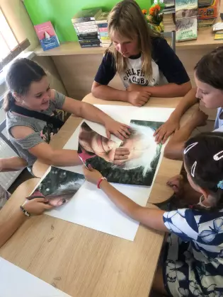 Dziewczyny układają z puzzli duży plakat Wisławy Szymborskiej.