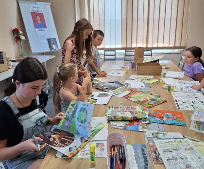 Uczestnicy zajęć wycinają z kolorowych gazet obrazki.