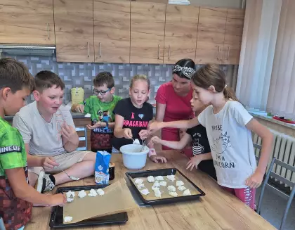 Dzieci układają na blaszkę do pieczenia ciasteczka.