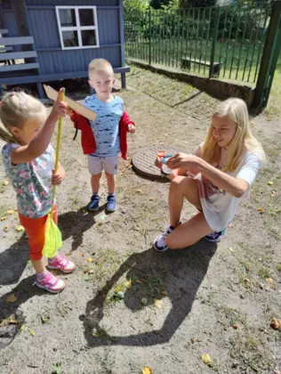 Dzieci łapią siatką owady i zamykaja je w plastikowym pojemniku w celu obserwacji.