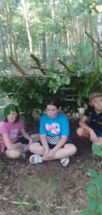 Dzieci siedzą pod szałasem.