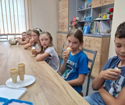 Dzieci jedzą lody w wafelku.