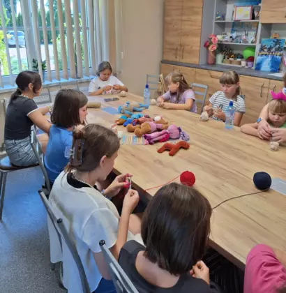 Uczestniczki siedzą przy stole i uczą się podstawowych splotów.