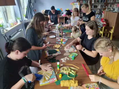 Uczestniczki wycinają sznurki, wyczesują oraz przyklejają listki do tekturki.