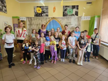 Wspólne zdjęcie dzieci razem z aktorkami oraz panią bibliotekarką na tle scenografii przedstawienia.