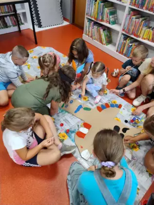 Dzieci na podłodze malują farbami duży posąg wodza indiańskiego wykonany z tektury.