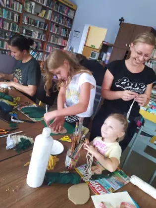 Uczestniczki przyklejają listki do tekturki.