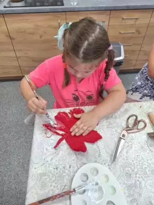 Dziewczynka smaruje liść klonu klejem.