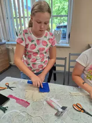 Uczestniczka zajęć wyczesuje szczotką sznurek.