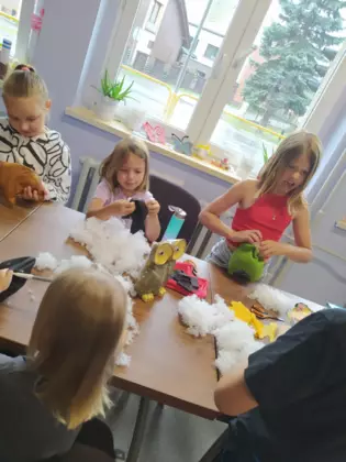 Dzieci szyją sówki i wypełniają je watą.