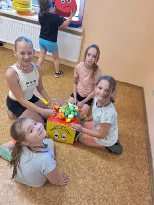 Dzieci na kostce budują piramidę z gniotków.