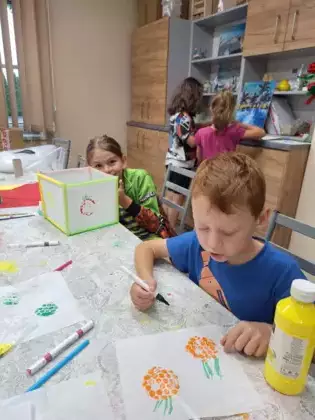 Chłopcy malują farbami owoce na lampionach.