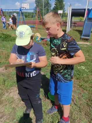 Chłopcy zapisują notatki dotyczące znalezionych owadów.