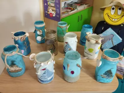 Prace plastyczne dzieci-słoiki pomalowane farbą i oklejone muszelkami.