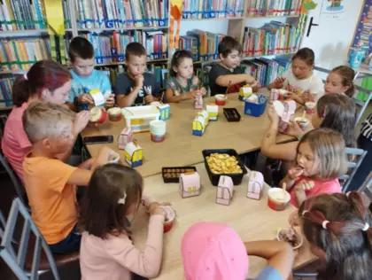 Uczestnicy siedzą przy stoliku i częstują się ciasteczkami.