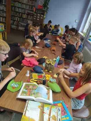 Dzieci szyją sówki i wypełniają je watą.