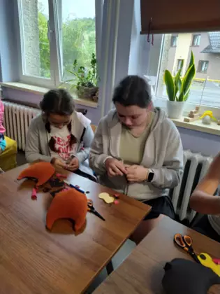 Dzieci szyją sówki i wypełniają je watą.