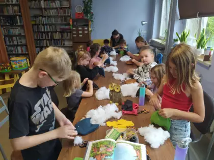Dzieci szyją sówki i wypełniają je watą.