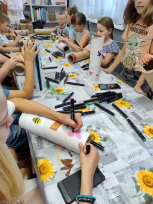 Dzieci kolorowymi mazakami malują tekturowe tuby tworząc domki dla owadów.