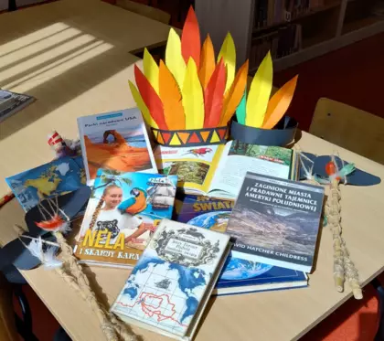 Książki i pióropusze leżą na stoliku.