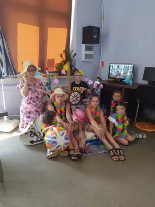 Wspólne zdjęcie uczestników zajęć z panią bibliotekarką na tle statku wykonanego z kartonu.