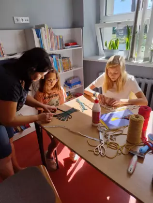 Dziewczyny według węzłów makramy układają sznurki tworząc listek.