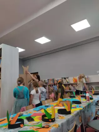 Uczestnicy wraz z panią bibliotekarką tworzą z tektury wodza indiańskiego.