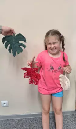 Dziewczynka trzyma w rączkach listki wykonane na zajęciach.