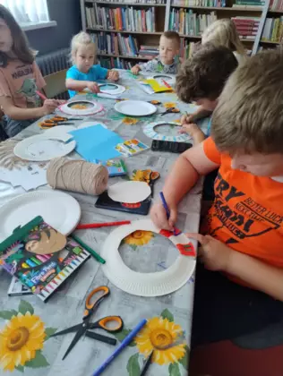 Z talerzyków papierowych dzieci robią afrykańskie naszyjniki.