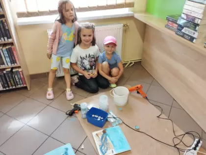 Dziewczynki przyklejają muszelki gorącym klejem na gorąco.